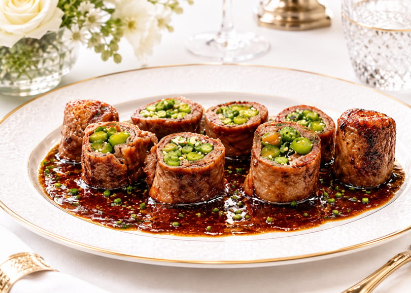 Seven beef rolls filled with green vegetables and sesame seeds, served in a rich brown sauce.