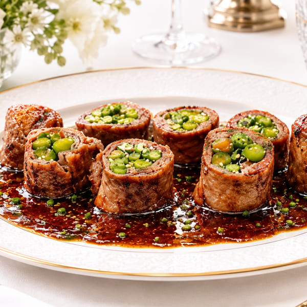 Seven beef rolls filled with green vegetables and sesame seeds, served in a rich brown sauce.